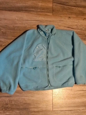 Ljusblå teddyjacka från Stories - Mysig turkos teddyjacka från Stories i storlek M.  Tillverkad i fluffigt teddy-material som håller dig varm och stilen är avslappnad och trendig.