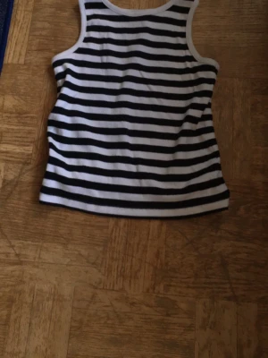 Randig svartvit linnetopp - Snygg ärmlös linnetopp med svarta och vita horisontella ränder. Klassisk modell med rund halsringning och ribbade kanter. Perfekt till sommaren och enkel att matcha med jeans eller shorts. Använt linnet en gång med min vita långkjol och det passar väldigt bra! (Säljer även kjolen)💕