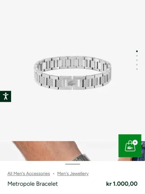 Metropole armband i stål från Lacoste - Snyggt Metropole armband från Lacoste i silverfärgat rostfritt stål. Armbandet har en länkdesign med matta och blanka partier samt den klassiska Lacoste-loggan på mitten. Perfekt accessoar för en stilren look.