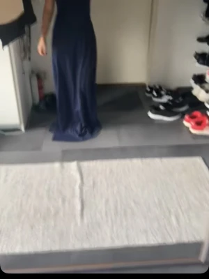 Marinblå långklänning med slits - Säljer en elegant marinblå långklänning med smala axelband och slits på sidan. Klänningen har en figurnära passform upptill och faller snyggt längs kroppen. Perfekt för dig som vill ha en stilren look med en touch av edge. Endast använd en gång. 