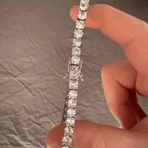 Silverfärgat tennisarmband med cz stenar - Snyggt tennisarmband i silverfärg med gnistrande, runda kubiska zirkon stenar i rad. Armbandet har en klassisk och stilren design med säkerhetslås, perfekt för dig som gillar bling. Arbandet är ca 23 cm. Kom privat för mer frågor