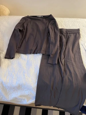  set med tröja och byxor - Säljer ett set som består av en långärmad tröja med rund hals och en par byxor med dragsko i midjan. Setet har en avslappnad passform och är gjort i mjukt, tunt stickat material. Perfekt för en chill och stilren look.