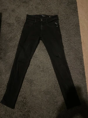 Svarta skinny jeans från Replay - Snygga svarta skinny jeans från Replay med klassisk femficksmodell och diskret logga på fickan. Jeansen har smal passform och är tillverkade i stretchigt material för extra komfort. Perfekta för en trendig och avslappnad stil.