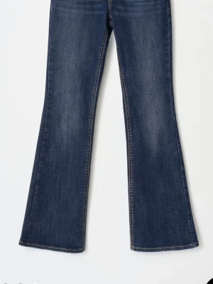 Mörkblå bootcut jeans - Snygga mörkblå bootcut jeans med klassisk femficksdesign och lätt utsvängda ben. Jeansen har en tidlös tvätt och kontrastsömmar som ger en cool look. Perfekta för dig som gillar retrovibbar och vill ha ett par jeans som sticker ut. Skriv för mer bilder. De har bakfickor med knapp