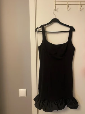 Svart klänning med volang - Svart klänning från AmyEnjoyLife i storlek XS. Klänningen har breda axelband, figurnära passform och en snygg volangdetalj längst ner. Perfekt för dig som gillar stilrena och trendiga plagg. Materialet känns mjukt och följsamt.💕🥹Säljer den då den tyvärr för för stor för mig. Men den är helt ny och oanvänd - endast testad.