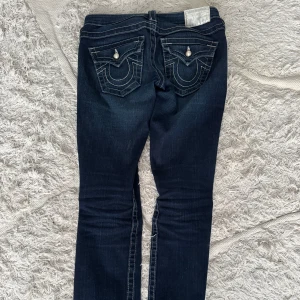 True religion jeans - Säljer nu mina älskade mörkblåa true religion jeans med fina detaljer pga att de är för små. De är lågmidjade och lite bootcut. De är i storlek 25 men skulle snarare säga att de är i 24 eller lite mindre. Har sprätt upp kanten där nere för att få dem längre men inget man tänker på. Pris går att diskuteras💞