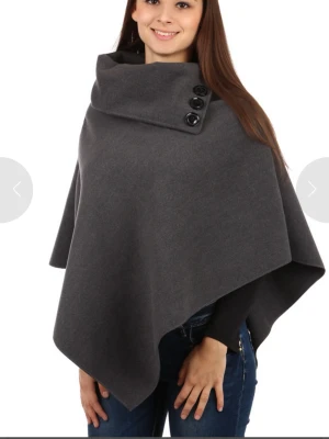 Mörkgrå poncho med knappar - Stilren mörkgrå poncho med ett mjukt tyg som ger en snygg drapering. Perfekt att slänga över en tröja för extra värme och stil. Passar alla