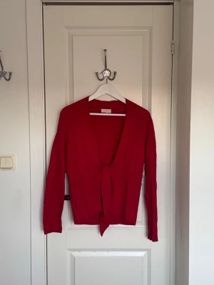 Röd knytkofta  - Snygg röd kofta med knytband framtill. Koftan har lång ärm och är tillverkad i ett mjukt, tunt material. 