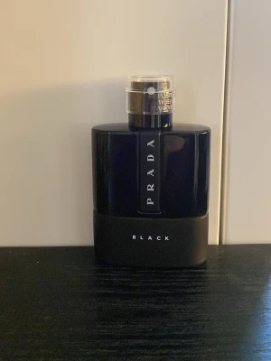 Prada Black parfym 100ml - Snygg parfymflaska från Prada i modellen Black. Flaskan är svart med en stilren, modern design och har en silvrig spraykork. Passar perfekt för dig som gillar exklusiva dofter och vill ha en elegant accessoar på hyllan.