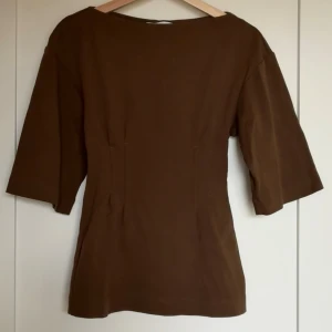 Topp med intagen midja  - En lång topp i kraftig bomullstrikå med båtringning och intagen midja både fram och bak.  Köpt förra sommaren, men aldrig använd, endast tvättad.   Från rökfritt hem men vi har hundar.