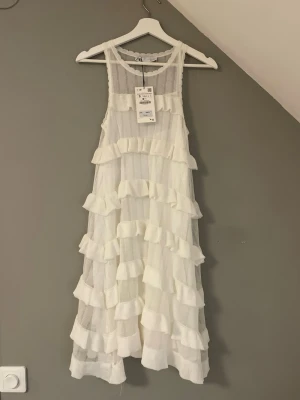 Vit volangklänning från Zara - Helt ny oanvänd vit kort volangklänning från Zara. Prefekt som studentklänning eller sommarklänning. Har underklänning för att inte bli genomskinlig. Nypris 379kr💕