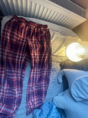 Rutiga pyjamasbyxor Björn Borg - Mysiga pyjamasbyxor från Björn Borg i rött, vitt och lila rutigt mönster. Byxorna har resår i midjan med Björn Borg-logga och är tillverkade i mjukt tyg, perfekta för chillkvällar hemma.