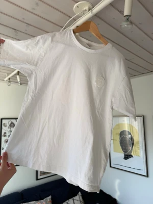 Vit t-shirt från bape  - Klassisk vit t-shirt från BAPE med rund hals och diskret logga på bröstet. Tillverkad i mjuk bomull och har normal passform med korta ärmar. Perfekt basplagg för alla tillfällen. SITTER SOM LARGE