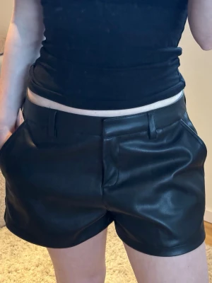 SKINNSHORTS  - Snygga svarta shorts i skinnimitation med normal passform och sidofickor.🌸🩷  Shortsen har bälteshällor och låg midja. Perfekta för att lyfta vilken outfit som helst - perfekta för alla tillfällen och passar alla stilar! 🤍🪩🩷Säljs då dem tyvärr är för stora för mig. Prislapp kvar. 