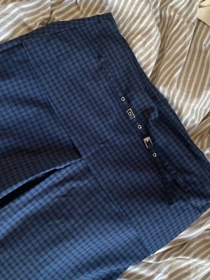 Mörkblå rutiga kostymbyxor - Snygga mörkblå kostymbyxor med diskret rutmönster och raka ben. Byxorna har dekorativa metallöglor vid linningen och raka ben. Helt nya!!
