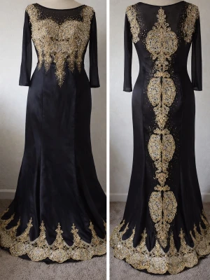 Elegant svart aftonklänning med lyxiga gulddetaljer - Vacker svart långklänning i satinliknande tyg med exklusiva guldbroderier och glittrande kristaller både fram och bak. Klänningen har en figurnära passform upptill som övergår i en elegant utsvängd nederdel, vilket ger en väldigt smickrande silhuett. Den broderade nederkanten och de detaljerade dekorationerna ger ett lyxigt och unikt intryck. Perfekt för fest, bröllop, gala eller andra speciella tillfällen där du vill sticka ut med något elegant.