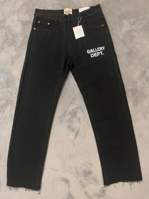 Svarta jeans från Gallery Dept. - Svarta jeans från Gallery Dept. med vit logotyptryck på vänster lår. Helt ny ✅ Inga defekter ✅Anledningen för att jag  säljer den är för att jag inte använder Baggy jeans.