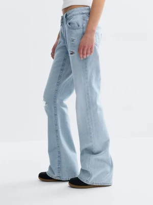 Ljusblåa vida jeans med slitningar - Säljer ett par ljusblåa jeans med bred passform och slitna detaljer på låret och knät. Jeansen har klassiska fem fickor och låg midja. Materialet är denim i bomull och bakfickorna har snygga sömmar. Perfekta för en avslappnad och trendig look. Använda en gång