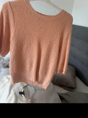Persikofärgad stickad tröja Holly & Whyte - Persikofärgad stickad tröja från Holly & Whyte med rund halsringning och ribbade muddar. 