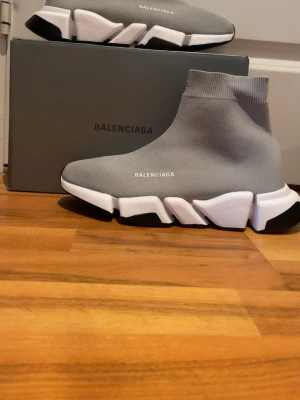 Grå Strumpskor Speed Trainer 2.0 sneakers - Grå Strumpskor 2.0 Speed Trainer sneakers med stickad ovandel i textil, vit och svart chunky sula och logga på sidan. Strumpliknande passform och modern design som sticker ut. Perfekta för dig som gillar streetwear och vill ha något unikt.