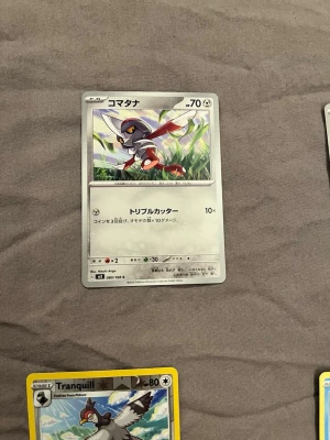 Japansk Pokémonkort Komatana - Säljer ett japanskt Pokémonkort med Komatana-motivet. Kortet har en vit och grå bakgrund med färgstark illustration av Pokémonen i gräs. Texten är på japanska och kortet har klassisk rektangulär form. Perfekt för samlare eller Pokémonfans.