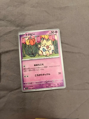 Pokémonkort Togepi japansk - Japanskt Pokémonkort med Togepi-motiv. Kortet har en lila bakgrund och visar Togepi bland färgglada tulpaner. Texten är på japanska och kortet har klassisk Pokémon-design med HP och attacker.