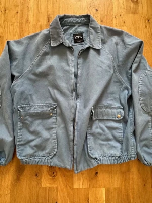 Grå utilityjacka från ZARA - Cool grå/blå utilityjacka från ZARA med dragkedja framtill, två stora fickor med lock och knappar ny pris 699 finns ej att få tag på