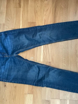 Mörkblå slimmy star jeans lagar157 - Säljer ett par mörkblå jeans med rak passform och klassisk femficksdesign från lager 157. Jeansen har subtila slitningar och är tillverkade i denim med snygg tvätt. Perfekta för en avslappnad och stilren look.