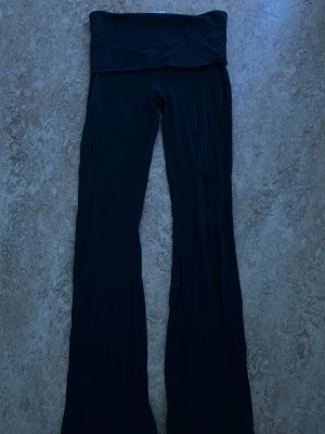 Svarta bootcut vikbyxor - Säljer ett par svarta leggings med bootcut-modell och låg midja. Mjukt och stretchigt material som sitter skönt på kroppen. Perfekta för dig som gillar en avslappnad men ändå trendig look.