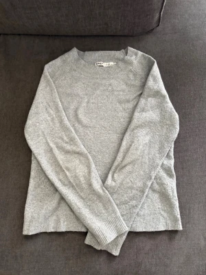 Ljusgrå stickad tröja från ONLY - Mysig ljusgrå stickad tröja från ONLY med rund halsringning och ribbade muddar vid ärmslut och nederkant. Perfekt basplagg till garderoben och enkel att matcha med olika stilar.