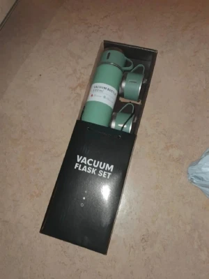 Grön vakuumtermos set 500ml - Snyggt set med grön vakuumflaska på 500 ml och två matchande muggar. Flaskan håller drycken varm eller kall i upp till 12 timmar. Perfekt för utflykter eller skolan. Kommer i originalförpackning. Materialet är rostfritt stål och plast.