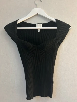 H&M topp - Snygg svart topp från hm som ser jätte liten ut men är väldigt stretchig! knappt använd storlek xs🥰🥰 
