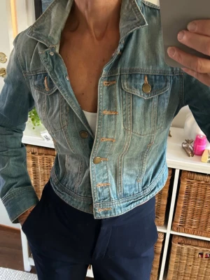 Ljusblå jeansjacka jeans jacka från 365 Sunshine - Säljer en ljusblå, croppad jeansjacka från 365 Sunshine. Klassisk modell med bröstfickor, bronsfärgade knappar och snygga sömdetaljer. Insidan har ett randigt foder i vitt och rött. Perfekt för dig som vill ha en cool och tidlös look. 