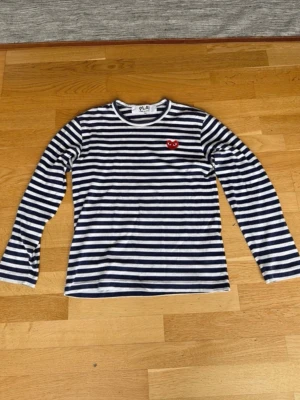 Comme des garcons randig långarmad - Säljer denna sjukt snygga comme des garcons långarmade med vit blå ränder (ser ut lite som svarta ränder på första bilden, men det är blå). Tröjan är i bra skick.