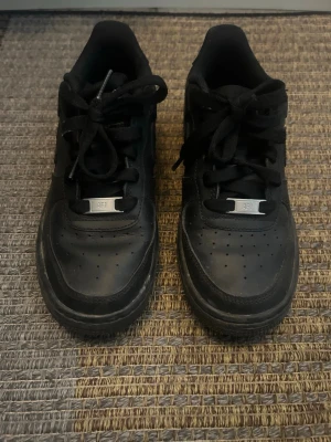 Svarta Nike Air Force 1  - Klassiska helsvarta Nike Air Force 1 sneakers med låg profil och rund tå. Skorna tvättas såklart innan jag skickar. 