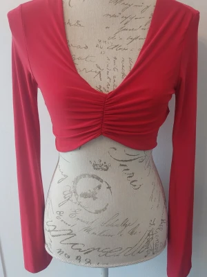 Röd kort top - Klarröd kort top. Mjuk och skön i viskos. Lång ärm med brett avslut. 