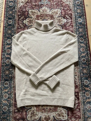 Beige polotröja i kaschmir - Säljer en beige 100% kaschmir polotröja från Davida Cashmere i storlek M. Den är knappt använd och är extremt mjuk och bekväm. Säljer denna p.g.a att jag aldrig använder den.
