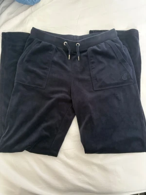 Mörkblå velourbyxor med fickor från juicy - Säljer mina älskade marinblåa juicy byxor i stl 15/16 år vilket mostvarar ungefär S🌸 köpta på kidsbrandstore🌸dom är i bra skick förutom en liten defekt som knappt syns (se bild 3) därav det billiga priset🌸jag är 167 cm lång, brukar ha M i vanliga fall och dessa är sneppet för korta för mig🌸