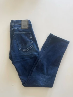 Mörkblå jeans från Replay - Snygga mörkblå jeans från Replay med klassisk femficksdesign och diskreta slitningar. Jeansen har raka ben och detaljerade sömmar på bakfickorna. Tillverkade i ett mjukt denimtyg som ger en skön passform. Perfekta för en avslappnad och trendig look. Hör av er med frågor!!!!