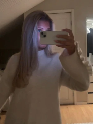 Vit stickad tröja med volangärm - Superfin vit stickad tröja från Arket med volangdetaljer längs ärmarna. Tröjan har en rund hals och är mjuk och fluffig i materialet, perfekt för att ge en mysig vibe till din outfit. Super trendig och helt slutsåld!!