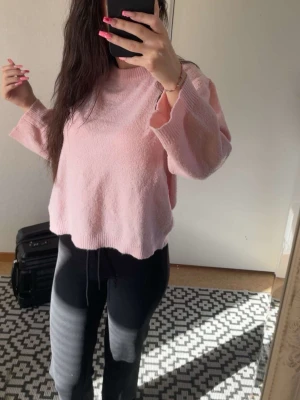 Ljusrosa oversized stickad tröja - Mysig ljusrosa stickad tröja med avslappnad, oversized passform och vida ärmar. Tröjan har rund halsringning och ribbade kanter nedtill. 