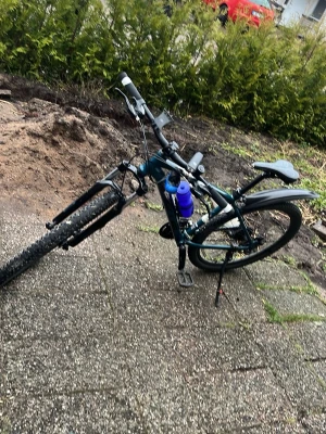 Blå mountainbike med stänkskärmar - Säljer en blå mountainbike med svart sadel, stänkskärmar och vattenflaska i hållare. Cykeln har grova däck, handbromsar och flera dekaler på ramen. Perfekt för dig som gillar att cykla i terräng eller på grusvägar.