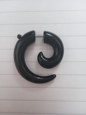 Fejk piercing/örhänge  - En fejk spiral piercing som är ett örhänge. Ger illusionen av ett sträckt öronlob genom att man skruvar på örhänget som är split itu. Örhänget är svart och har inga skador men är däremot använd. Köptes på CrazyFactory. Den är ungefär 3,3 cm i den horisontelal diametern. För exakta mått och fler bilder var vänlig och kontakta.
