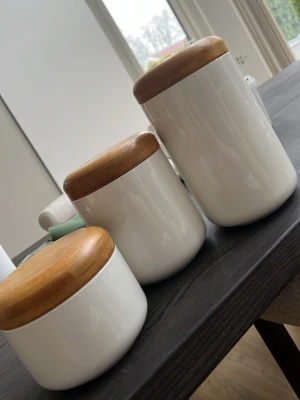 Vita burkar med bambulock - Säljer tre stilrena vita förvaringsburkar i keramik med runda lock i bambu. Perfekta för att förvara te, kaffe eller småsaker. Locken har silikonring för tät förslutning och burkarna har en enkel, modern design.