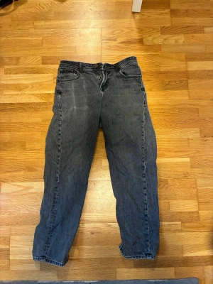 Svarta Jack and Jones jeans - Säljer ett par svarta jeans i loose fit model. Jeansen har klassisk femficksdesign. Väldigt slitna i färgen med defekter som syns på bilderna.Perfekta till en avslappnad streetstyle-look.