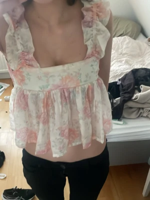 Blommig volangtopp i pastellfärger - Söt blommig topp med volangdetaljer och breda axelband i storlek xs. Toppen har en luftig, flowy passform och är i ljusa pastellfärger som rosa, vit och lite grön. Perfekt för varma dagar. toppen är i väldigt bra skick har bara blivit använd 2-3 gånger ungefär. hör av dig om du har några frågor eller funderingar 💕