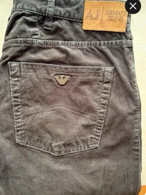 Svarta manchesterbyxor från Armani Jeans - Snygga svarta manchesterbyxor från Armani Jeans med klassisk femficksdesign och AJ-logga på bakfickan. Byxorna har en rak passform och är tillverkade i mjuk manchester för en cool och bekväm stil. Perfekta för dig som gillar streetwear och premiumkänsla.