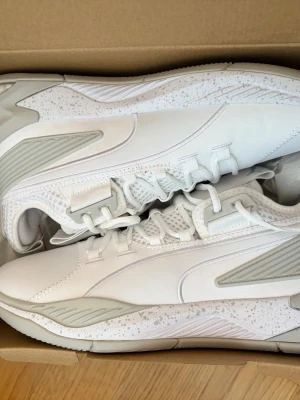 Vita sneakers från Puma - Stilrena vita sneakers från Puma med detaljer i ljusgrått och speckle-mönster på sulan. 