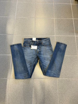 Blå  jeans från tiger of sweden - Säljer ett par klassiska blå jeans från tiger of sweden med raka ben och femficksmodell. Jeansen har snygg tvättad look och är tillverkade i slitstark denim. Perfekta för dig som gillar en tidlös och avslappnad stil.