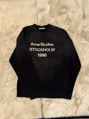  Acne Studios långarmad tshirt - Cool svart sweatshirt från Acne Studios med vit text 'Acne Studios STOCKHOLM 1996' på bröstet. Storlek S. 